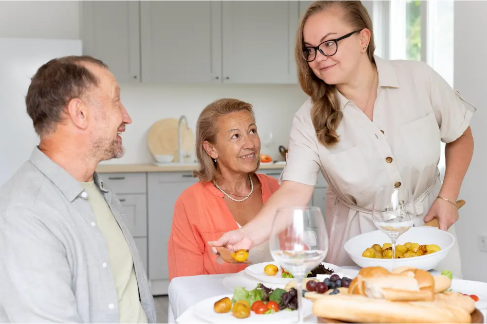carer serving food to elderly couple in their home