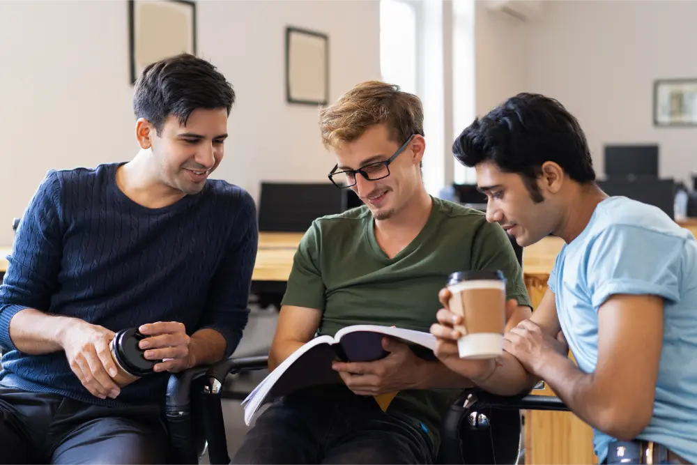 three students reading textbook together drinking
